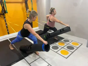 Image of two students benefiting from our buddies program where two friends can work out together. They are working out using bands and ViPR training